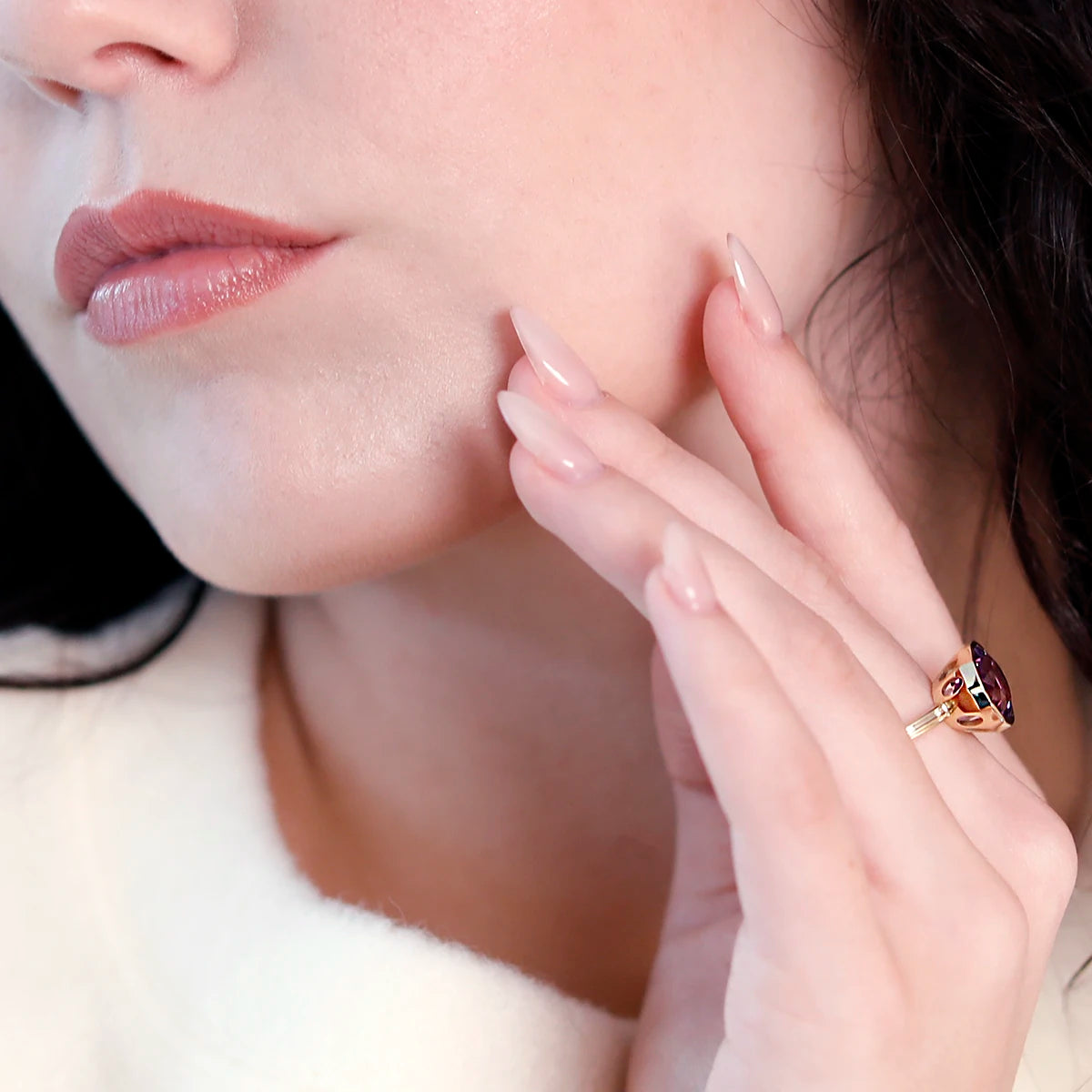 Side view of a woman wearing a statement amethyst ring by Bena Jewelry. The yellow gold band and large, fancy-shaped amethyst with deep purple hues create an elegant and eye-catching design.