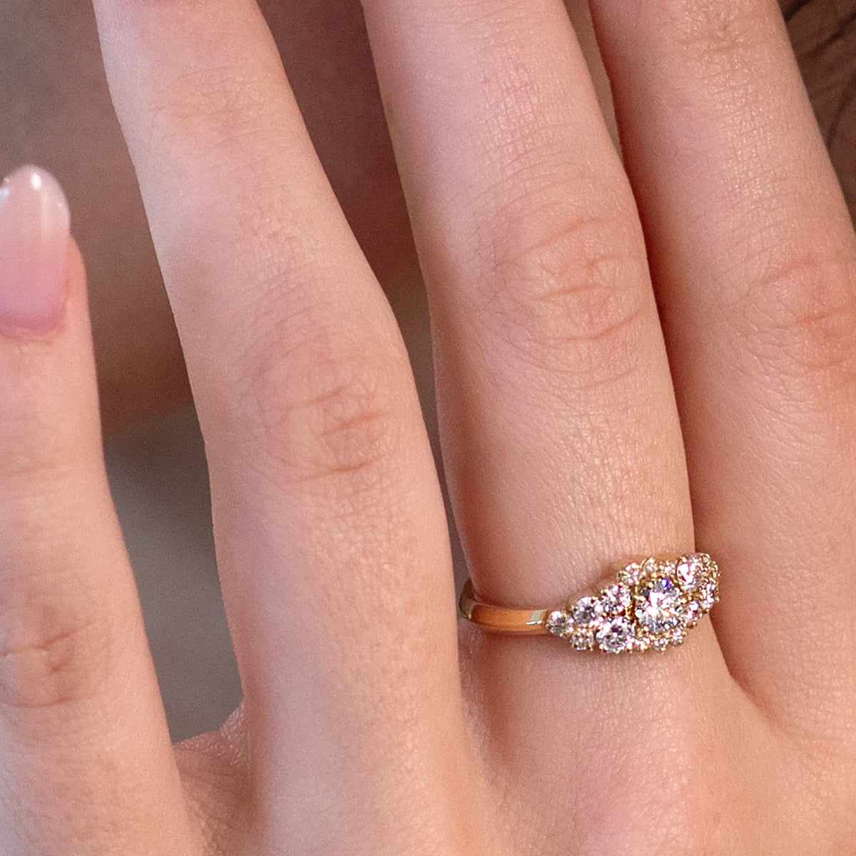 Close-up of a handcrafted yellow gold ring with 17 lab-grown round brilliant diamonds, designed by Bena Jewelry. The image captures the exquisite details and brilliance of the piece as it rests elegantly on the finger.