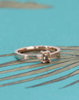 Close-up of Bena Jewelry's rose gold ring with an orange sapphire and diamond accents, set against a white background.
