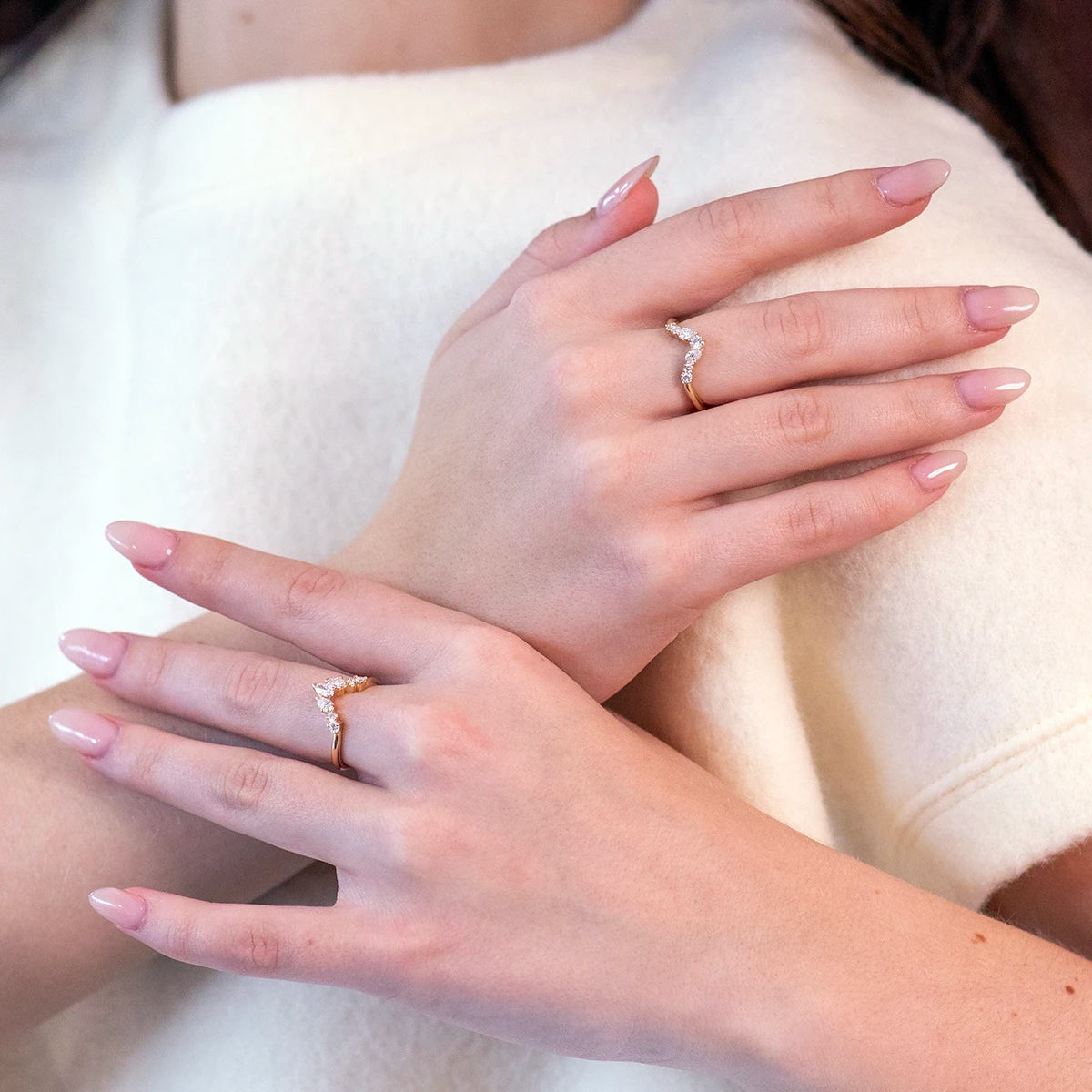 Elegant shot of two hands wearing individual stackable diamond wedding bands by Bena Jewelry. Each ring features round and pear-shaped diamonds, showcasing modern sophistication.