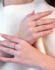 Elegant shot of two hands wearing individual stackable diamond wedding bands by Bena Jewelry. Each ring features round and pear-shaped diamonds, showcasing modern sophistication.
