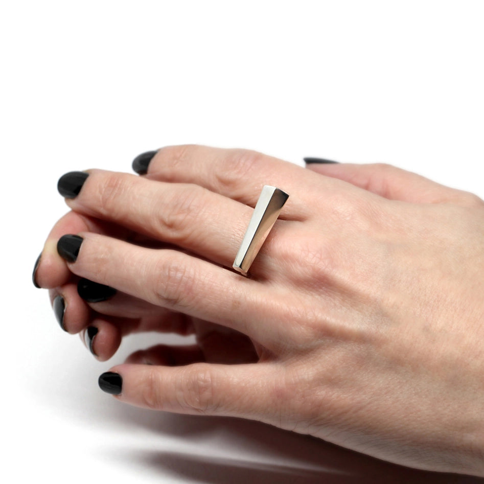 Unisex statement white gold ring designed in Montreal by Bena Jewelry, seen in close-up worn by a hand with black nails. Ready-to-wear fashion jewelry available online or in Montreal's Little Italy.