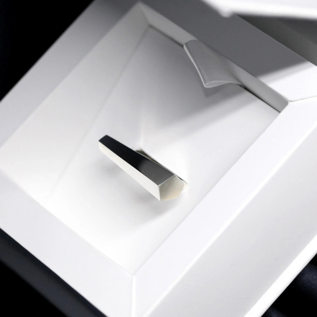 Sturdy ring in white gold photographed on the shadows. A Minimalist, modern and elegant piece of jewelry. Find this gender-neutral ring that fits both classic and edgy wardrobes online or at Bena Jewelry's store in Montreal Little Italy.