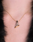Close-up of an architectural pendant in 14k yellow gold with black enamel and pavé-set diamonds, featuring a bold triangular design. A sculptural statement necklace by Bena Jewelry, handcrafted in Montreal.