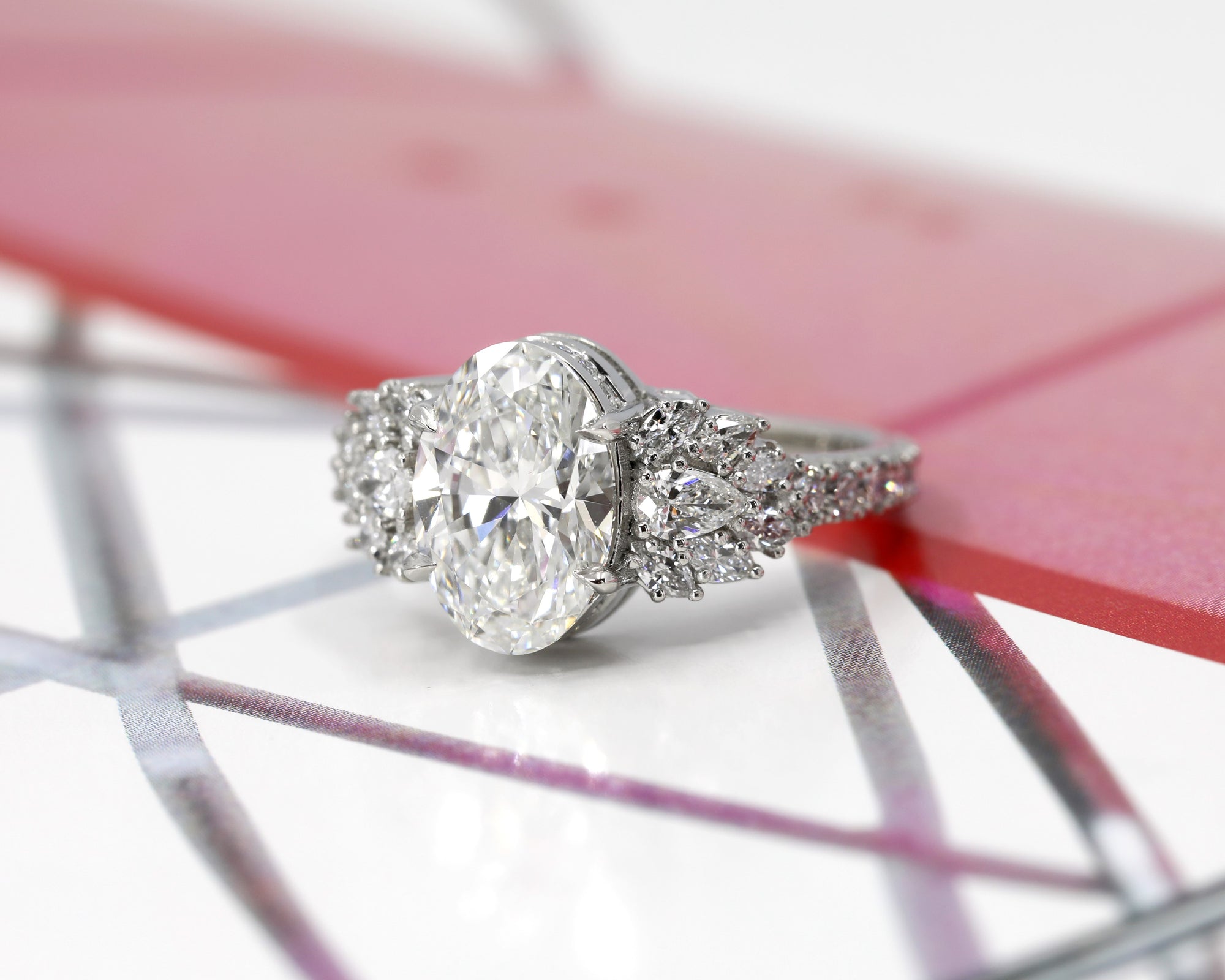 oval shape lab grown diamond and marquise shape designer side gems on platinum and round natural gemstone custom made in montreal by bena jewelry and boutique ruby mardi on multicolor background