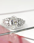 front view oval shape lab grown diamond and side gemstone designed by bena jewelry best bridal engagement ring desginer in montreal bespoke engagement ring in platinum and lab grown diamonds on multi color background