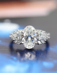 front view of oval shape lab grown diamond oval shape and side gemstone marquise and pear shape natural gems made with platinum bridal jewels on blue dark background