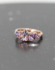 The "Avalanche" ring in 14k rose gold with lilac and purple sapphires, illuminated against a dark background to enhance the brilliance of the gemstones and the bold asymmetrical design. Fine jewelry crafted in Montreal by Bena Jewelry.