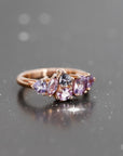 The "Avalanche" ring, set with lilac and purple sapphires in rose gold, showcased on a shadowy backdrop for a dramatic and elegant contrast. A modern masterpiece crafted in Montreal by Bena Jewelry.