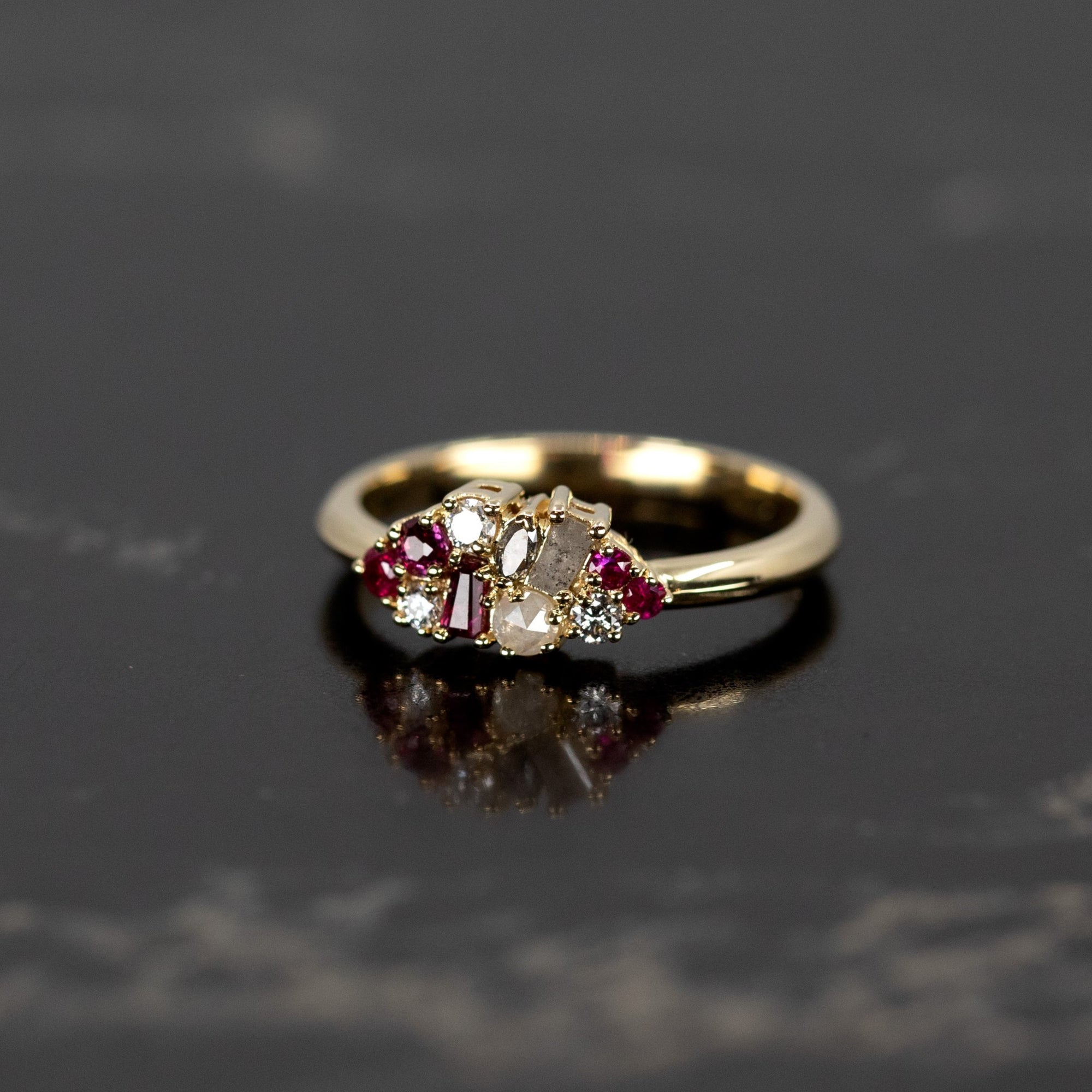 Ruby & Salt And Pepper Diamond Avalanche Ring with rubies and diamonds set in yellow gold, shot against a dark background to highlight its striking design.