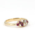 Close-up of Ruby & Salt And Pepper Diamond Avalanche Ring with unique design of rubies and diamonds set in yellow gold, photographed on a white background.