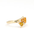 Close-up of the Kink Avalanche ring showcasing the twist design and vibrant orange and yellow sapphires, set in yellow gold.