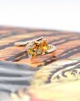 Artistic view of the Kink Avalanche ring by Bena Jewelry, featuring orange and yellow sapphires, diamonds, and a distinctive twist design in yellow gold, showcasing its bold and unique craftsmanship.