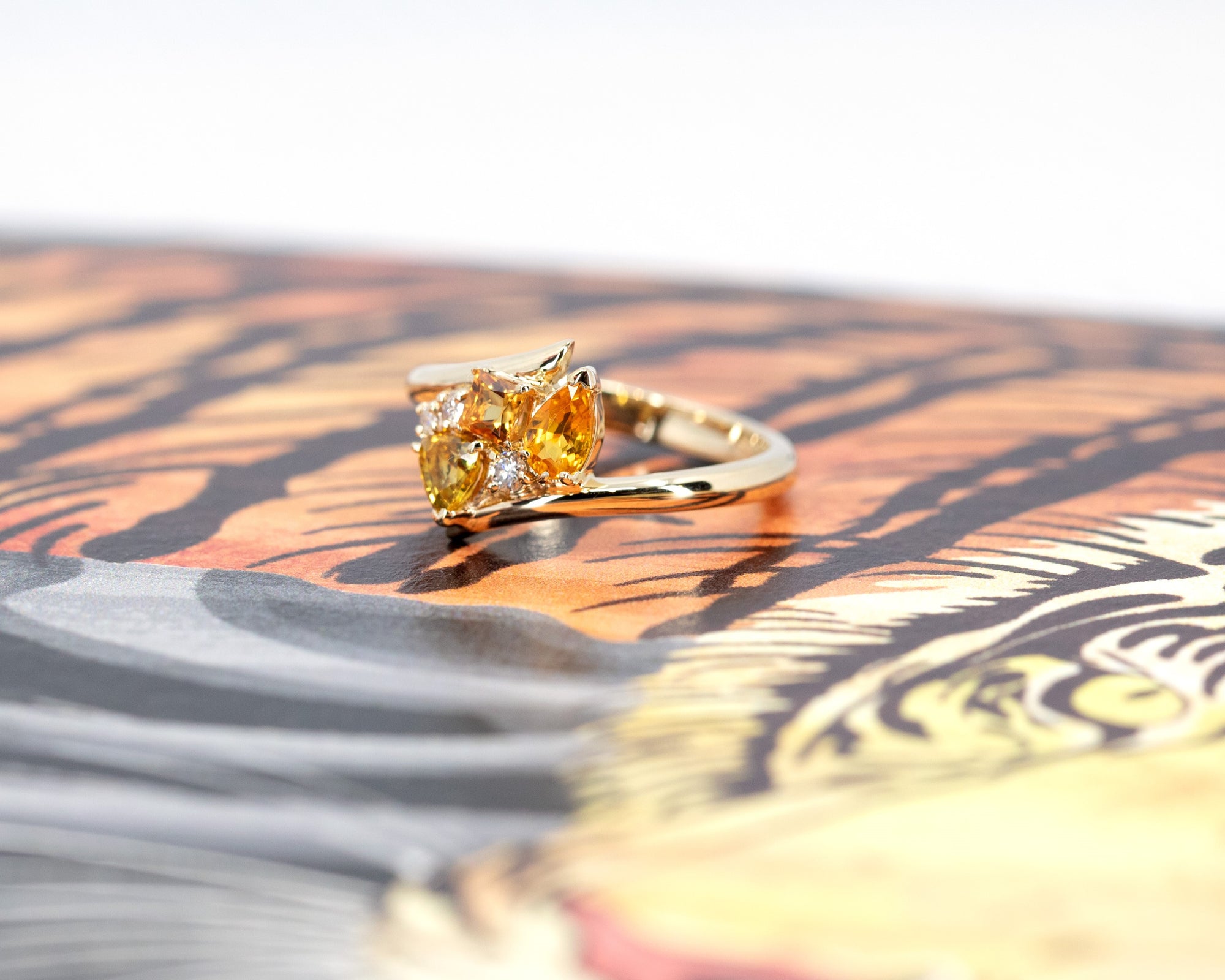 Side view of the Kink Avalanche ring, emphasizing the unique twist in the band and the bold arrangement of orange and yellow sapphires with diamonds.