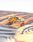 Side view of the Kink Avalanche ring, emphasizing the unique twist in the band and the bold arrangement of orange and yellow sapphires with diamonds.