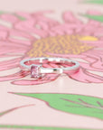 Modern white gold ring featuring a baguette-cut pink sapphire, styled on a rose-toned backdrop. Handmade by Bena Jewelry.