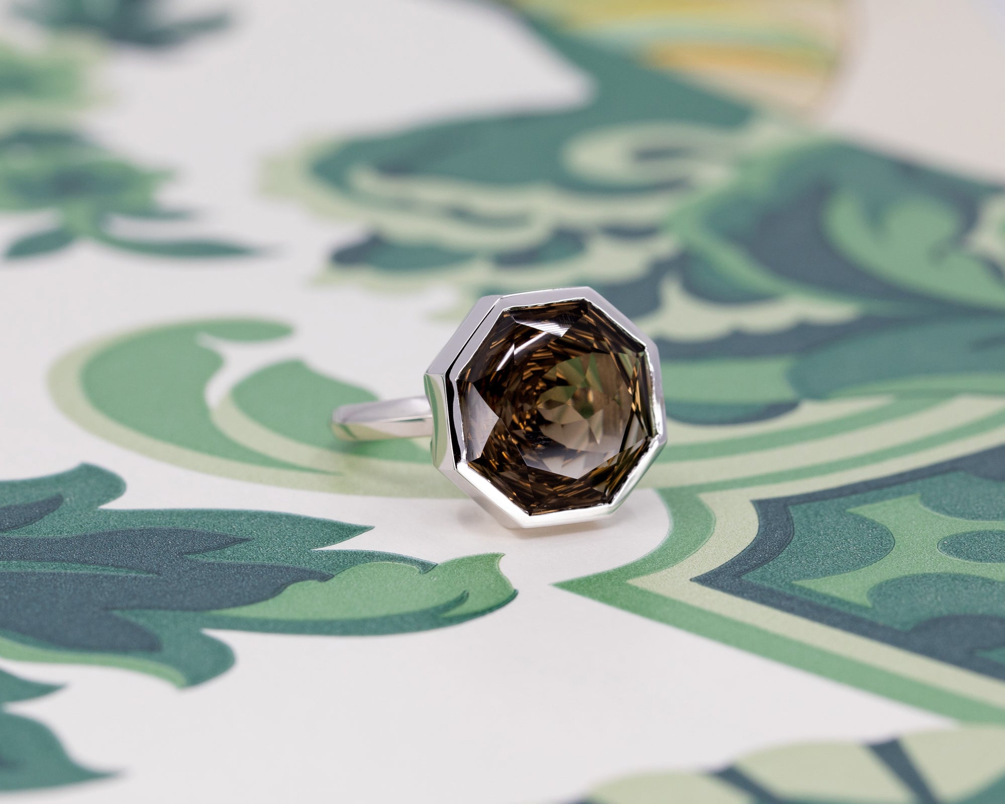 Octagonal smoky quartz ring in white gold, glowing against a bold colorful background, designed by Bena Jewelry.