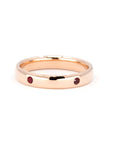 Custom men’s rose gold wedding band with round rubies, set against a soft-colored background. Designed by Bena Jewelry in Montreal.