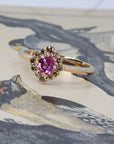 Artistic shot of Bena Jewelry’s pink sapphire and brown diamond ring on a textured background, showcasing its modern design and warm gold tones.