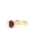 Side view of ruby engagement ring – A warm yellow gold band elegantly holding an oval ruby and two brilliant diamonds.