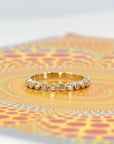 Custom yellow gold wedding ring with a bezel-set diamond, displayed on a vibrant colored background. A modern and bespoke design by Bena Jewelry, crafted in Montreal.