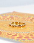 Yellow gold wedding band with a bezel-set extra-brilliant diamond, placed on a bold, colorful backdrop. Tailored bridal jewelry made by Bena Jewelry in Montreal, Canada.