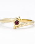 Kink Ruby ring with a blood-red round ruby in a bezel setting, mounted on yellow gold. Edgy twisted band design, handcrafted by Bena Jewelry in Montreal.