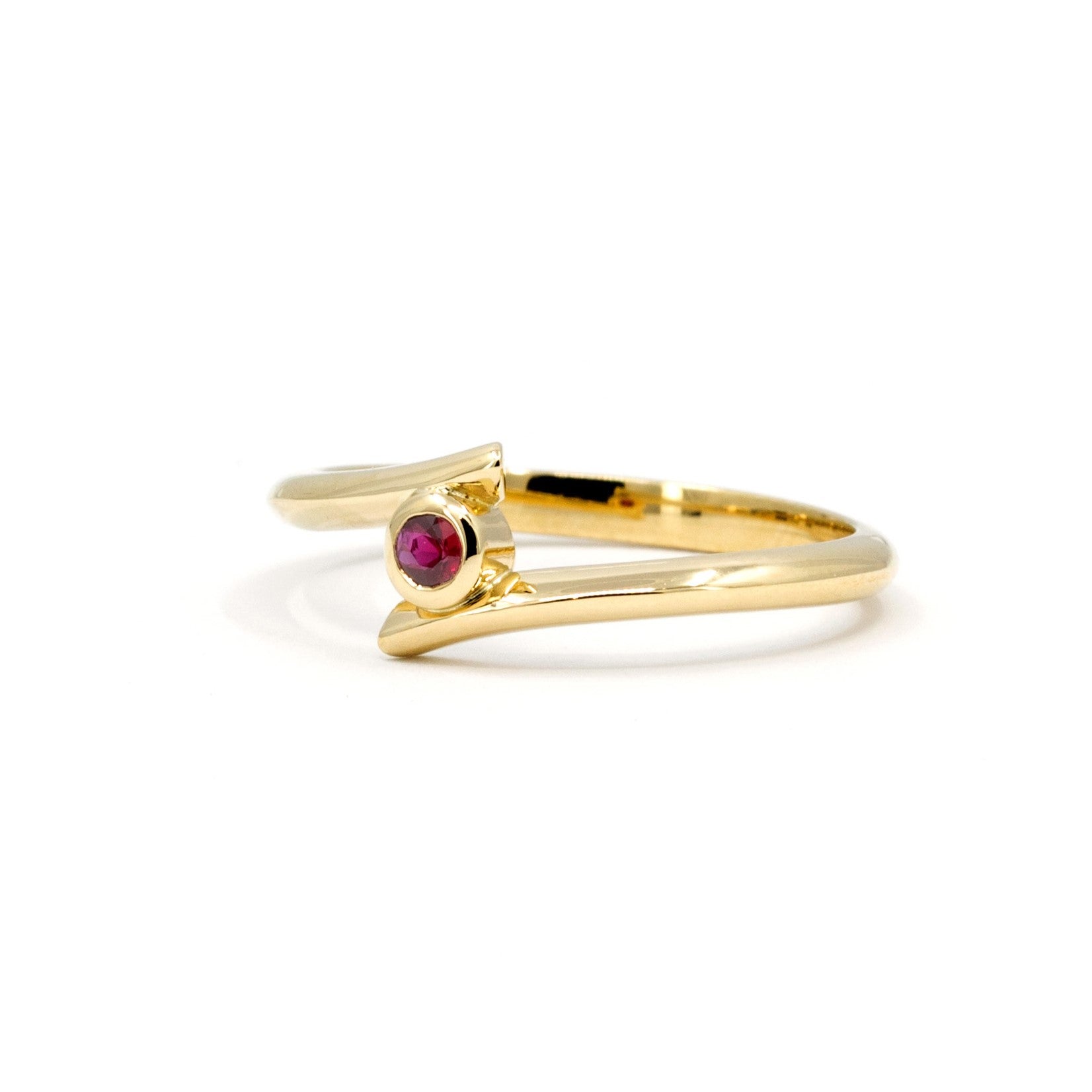 Close-up of the Kink Ruby ring showcasing its round blood-red ruby and twisted yellow gold band, designed by Bena Jewelry in Montreal.