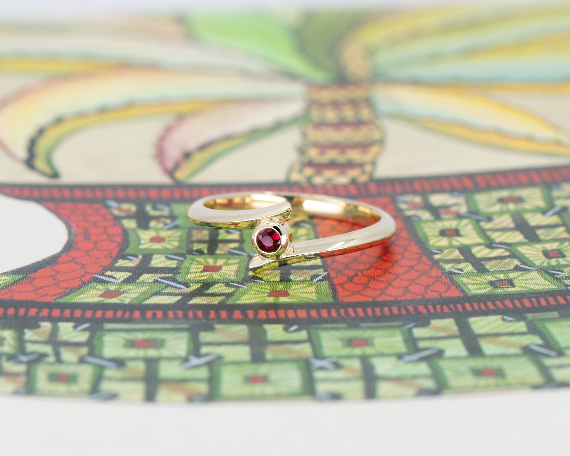 Yellow gold Kink Ruby ring with a bezel-set round ruby, featuring an edgy and unique twisted band design by Bena Jewelry, a fine jewelry designer in Montreal.