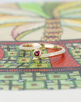 Yellow gold Kink Ruby ring with a bezel-set round ruby, featuring an edgy and unique twisted band design by Bena Jewelry, a fine jewelry designer in Montreal.
