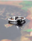 Modern black diamond ring in white gold, displayed on a vibrant colored background, crafted with precision and creativity by Bena Jewelry, a designer jeweler based in Montreal.
