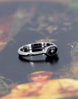 Artistic presentation of a hexagonal black diamond ring in white gold on a soft gradient background, emphasizing the sleek bezel setting and unique design by Bena Jewelry in Montreal, Canada.