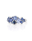 Angled side view: Highlights the interplay of royal blue and cornflower sapphires with the refined white gold band. Crafted by Bena Jewelry, Montreal, Canada.