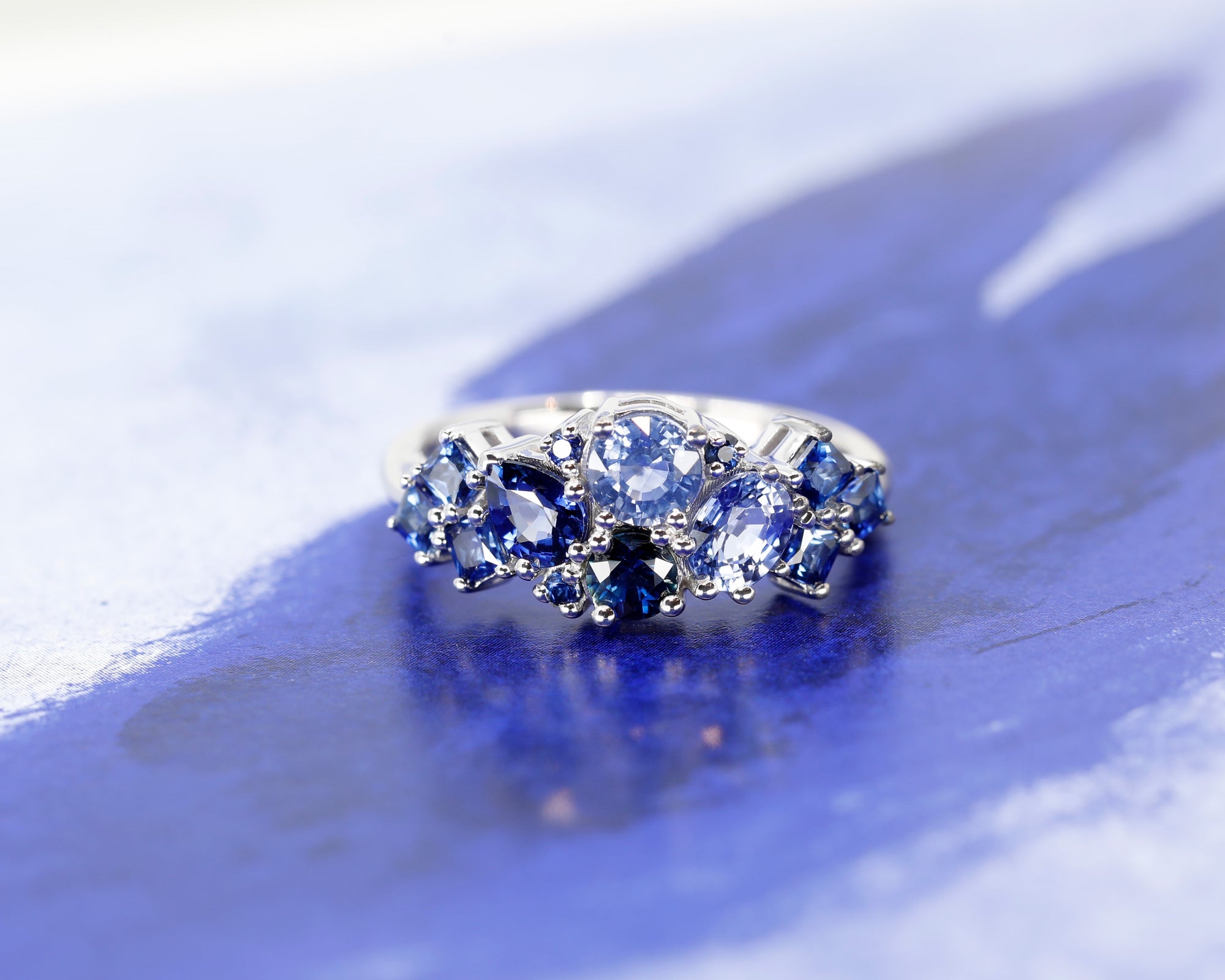 Front view: The Avalanche Blue Sapphire Ring against a dark background, emphasizing the contrast between the vibrant blue sapphires and the sleek white gold. Designed by Bena Jewelry in Montreal, Canada.