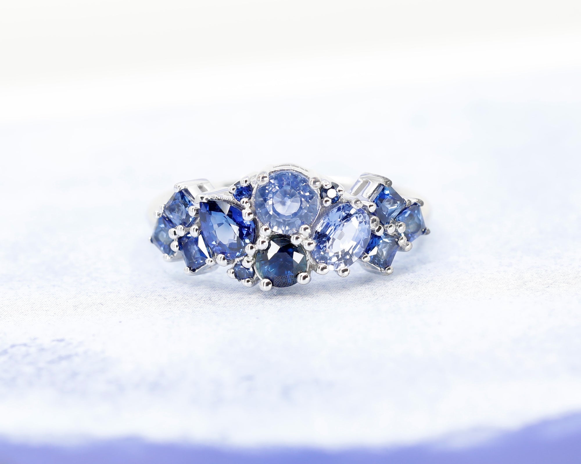 Top-down view: Displays the sapphire amalgamation and the seamless integration of the gemstones with the white gold band. Custom-made by Bena Jewelry in Montreal, Canada.