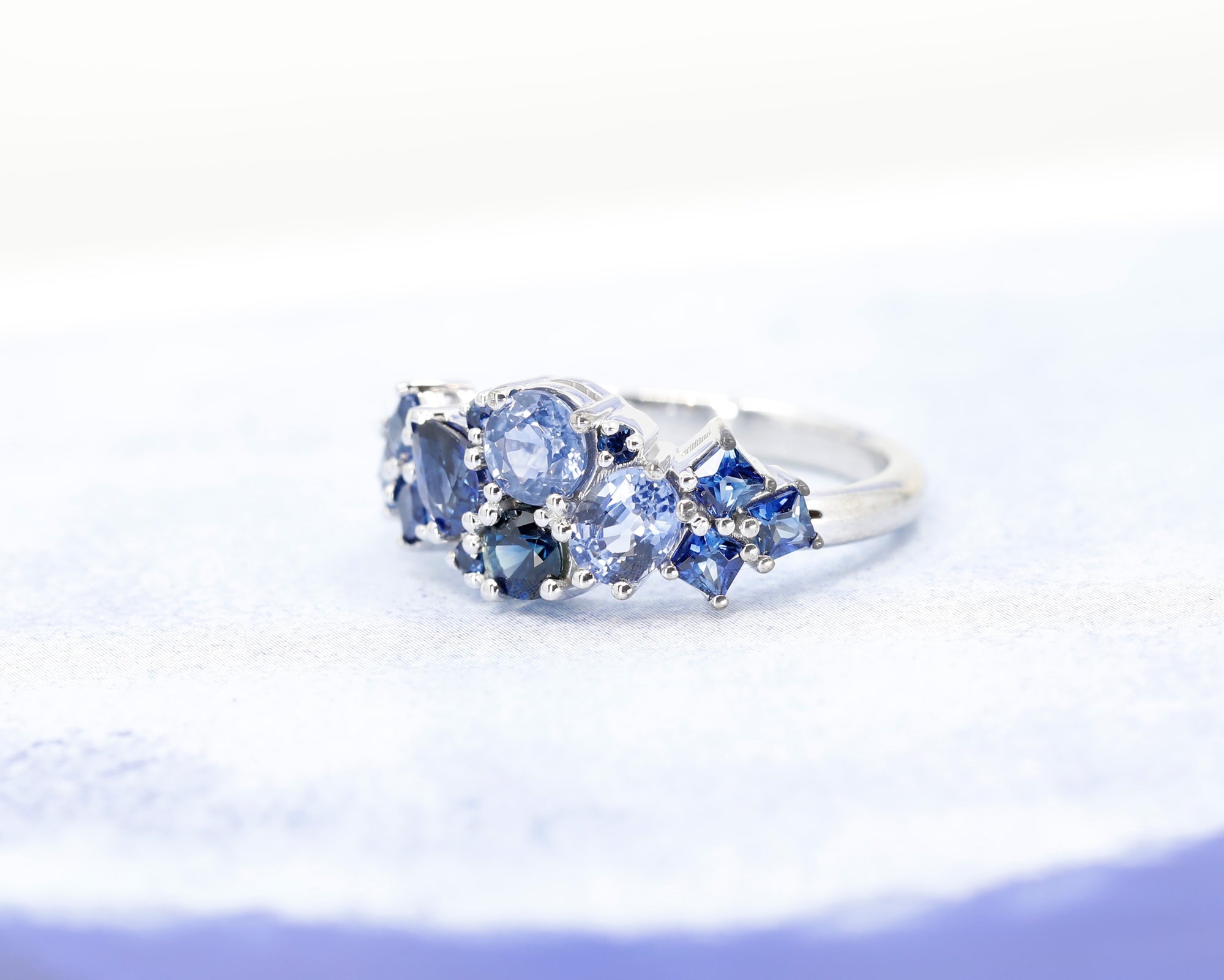 Close-up: Captures the vibrant hues of the sapphires and the smooth finish of the white gold setting. Made in Montreal, Canada, by independent designer Bena Jewelry.