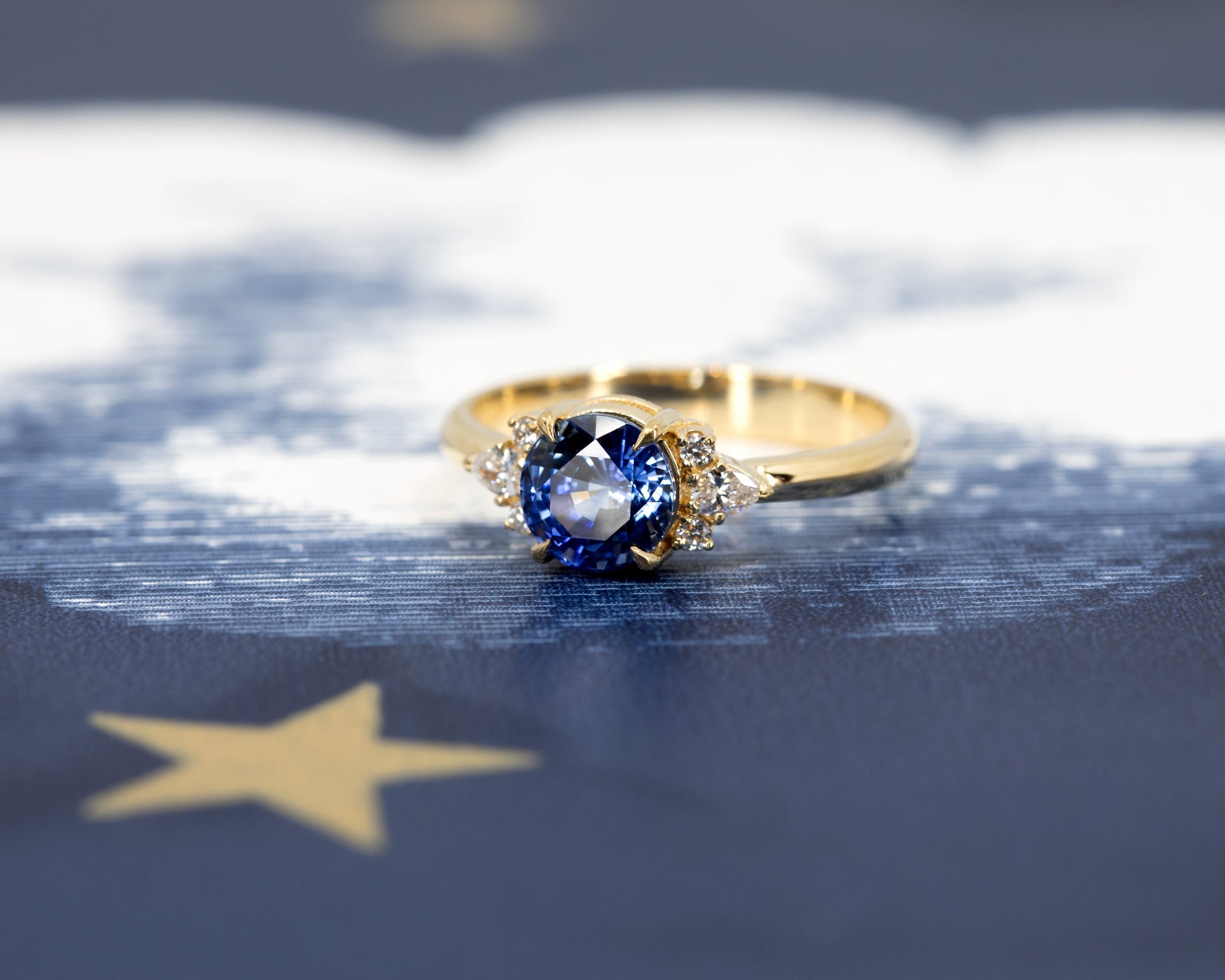 Close-up of Azure Tide Sapphire & Diamond Ring – A striking fine jewelry piece with a rich yellow gold setting and brilliant-cut side diamonds.