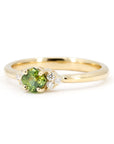 Detail of yellow gold ring with a cushion-cut green sapphire and diamond accents, displayed on a white background. Contemporary bridal jewelry by Bena Jewelry, made in Montreal.