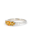 Product photography of a unique alternative engagement ring designed in Montreal by local brand Bena Jewelry. The white gold ring is seen on a white background. It features orange sapphires and diamonds.