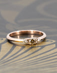 Elegant engagement ring by Bena Jewelry, featuring a champagne diamond and side stones, set in rose gold. Highlighted against a deep dark background, showcasing its brilliance and sophistication. Handmade in Montreal.