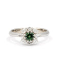 Close-up of the Deep Forest Glow ring in white gold, featuring a vibrant green sapphire at its center, surrounded by a diamond halo in a floral-inspired design. Handmade by Bena Jewelry in Montreal.