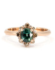 Close-up of a rose gold ring featuring an oval teal sapphire with a halo of brown and white diamonds, designed by Bena Jewelry in Montreal.