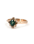 Teal sapphire halo ring in rose gold with mixed diamonds, handcrafted by Bena Jewelry, shown from a top-down angle on a white background.