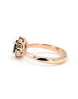 Side view of the Aura ring by Bena Jewelry with a deep teal sapphire and diamond halo, set in rose gold, photographed on a white surface.