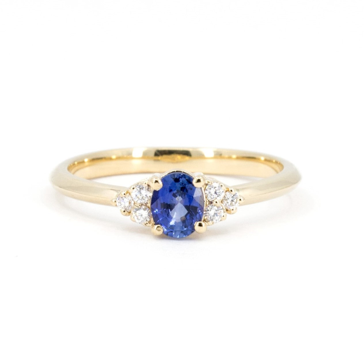 Desir Ring with an oval blue sapphire and diamond accents, set in yellow gold. A handcrafted engagement ring by Bena Jewelry, Montreal.