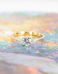 Yellow gold Round Diamond Desir Ring with a round-cut diamond and side stones by Bena Jewelry displayed on a soft pastel background custom bridal ring Montreal
