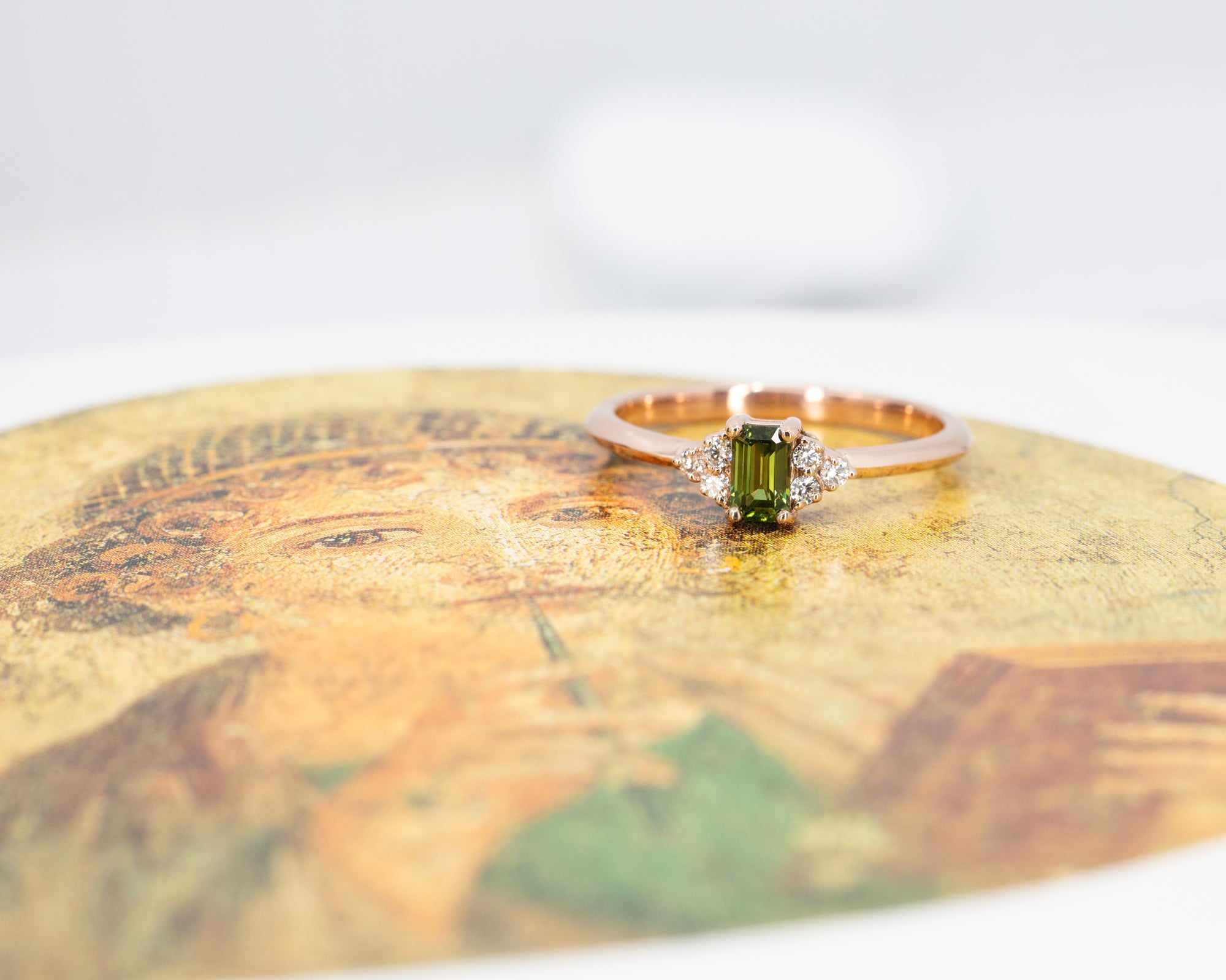 Unique rose gold engagement ring with a deep green sapphire and diamond accents Désir Ring by Bena Jewelry displayed on a black matte background