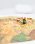 Unique rose gold engagement ring with a deep green sapphire and diamond accents Désir Ring by Bena Jewelry displayed on a black matte background