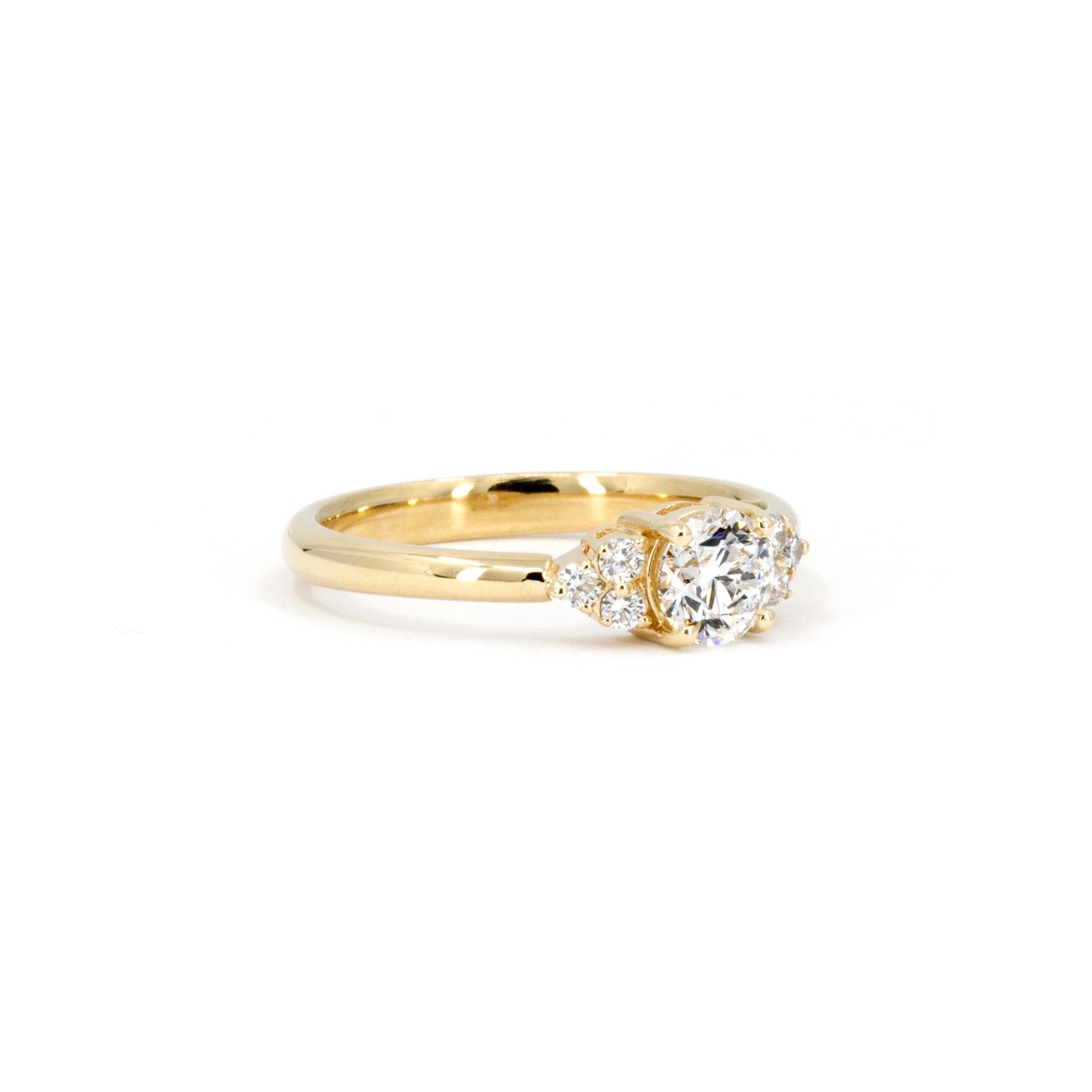 Classic yellow gold engagement ring with a central diamond and side accents, designed by Bena Jewelry, a Montreal-based jewelry designer.