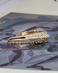 Edgy Bena Jewelry ring with pavé-set diamonds photographed on a vibrant colored background, emphasizing the contrast and sharp form of the gold design.